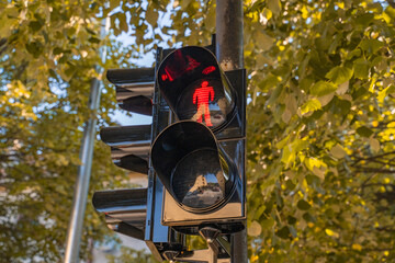 a black traffic light in the city showing a prohibitive signal for pedestrians against the...