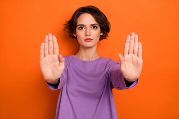 Photo of serious confident girl dressed purple pullover showing arms stop isolated orange color background