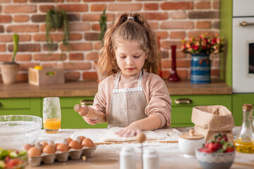 At the kitchen charismatic and beautiful girl using the kitchen roller to prepare the dough for...