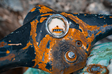 Close-up of an old rusty steering wheel of a two-wheeled motorcycle with a broken speedometer