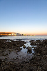 The rocky beach at Hope Gap on the Sussex coast, with a view of the Seven Sisters cliffs at sunset