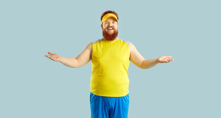 Funny happy fat man in yellow and blue sportswear standing isolated on blue background, smiling and...