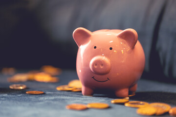 Um cofrinho sobre um sofá azul com moedas espalhadas. Conceitos de finanças do lar e economia.