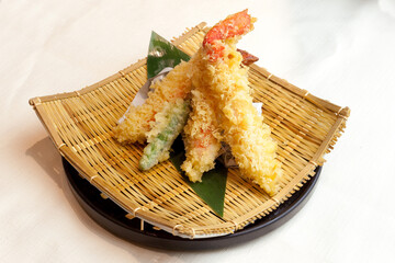 和食レストランや居酒屋で提供される、揚げたてでサクサクとした食感の蟹の天麩羅盛り合わせ。笹の葉を敷いた竹ザルに盛り付けられた、高級感のある一品料理。テキストを入れるスペースあり © Photo Craft