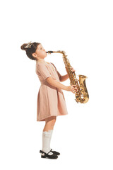 Charming little girl playing saxophone isolated on white studio background. Retro vintage style...