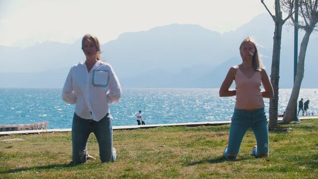 Two women doing simple gymnastics by the sea 