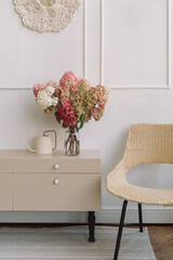 A beautiful bouquet of hydrangeas on a low chest of drawers in a modern cozy living room. Copy space.