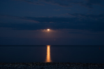 Night landscape. Full moon over the sea. Reflection of the moon path.