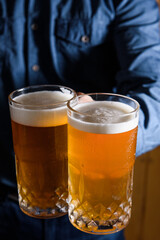 two glasses of beer in hand