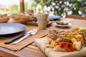 Tipical summer south Italian appetizer focaccia with cherry tomatoes and rucola served outdoor