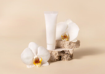 White cream tube near white orchid flower on light yellow, Mockup. Skincare product