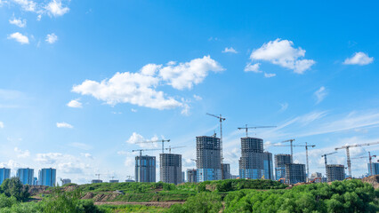 Fototapeta premium Construction of a multi-story residential buildings. A lot of construction equipment, cranes work. Construction site.