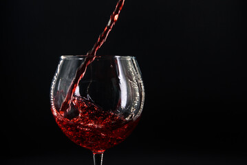 red wine pouring into a glass on a black background