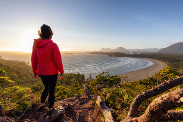 Adventurous Woman Hiker overlooking Sandy Beach on the West Coast of Pacific Ocean. Canadian Nature Landscape Background. Cox Bay Lookout, Tofino, Vancouver Island, BC, Canada.