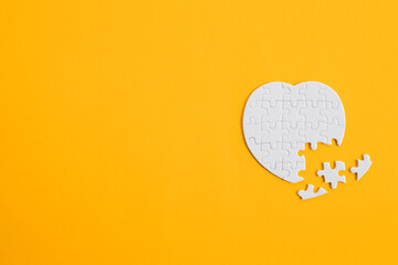 Puzzle heart with one missing piece on yellow, health care concept