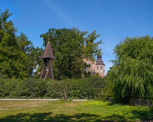 Obraz premium Façade of a gothic stone house and a church steeple in a park, a sunny summer day in Stockholm
