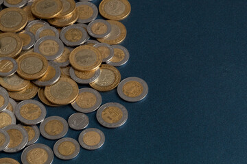 pile of mexican pesos coins, on a blue surface, with copy space