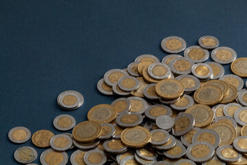pile of mexican pesos coins, on a blue surface, with copy space