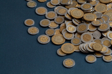 pile of mexican pesos coins, on a blue surface, with copy space