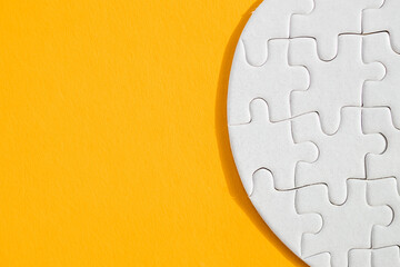 Heart-shaped jigsaw puzzle on color background.