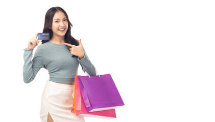 Trendy young Asian woman hold plastic credit card and shopping bags pointing up to credit card...