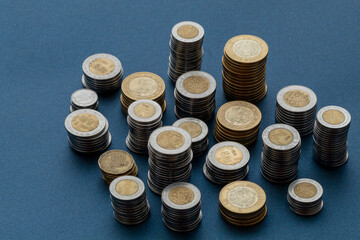 Piles of Mexican pesos coins, isolated at the center of the image with a blue background