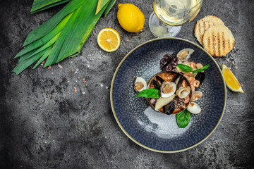 Mussels in clay bowl, glass of white wine and lemon on blue background. Mediterranean cuisine. Restaurant menu, dieting, cookbook recipe top view