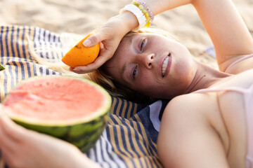 Cheerful young woman enjoy at tropical sand beach. Girl eating a fruit.