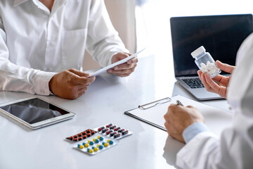 Fototapeta premium doctor or pharmacist advises patients about pills. The doctor prescribes medication sitting at a table in the clinic office. to find the best course of treatment. follow-up treatment
