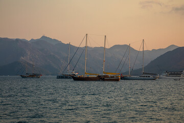 White yachts are in the bay at sunset. Calm sea. Mountains in the background. Beautiful evening in Marmaris.