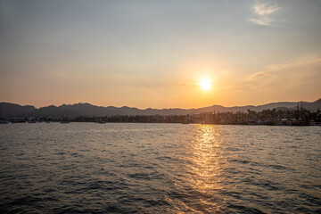 Beautiful and colorful sunset on the sea. Small sea town. Beautiful sky and mountains. Calm summer evening.