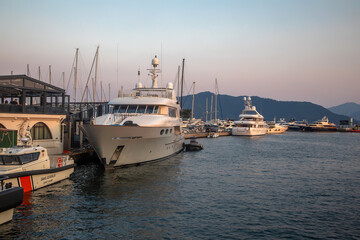 Fototapeta premium White yachts are in the bay at sunset. Calm sea. Mountains in the background. Beautiful evening in Marmaris.