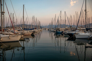 White yachts are in the bay at sunset. Calm sea. Mountains in the background. Beautiful evening in Marmaris.