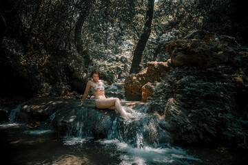 A beautiful girl in a bathing suit near a forest river. Stones and water. Green trees. Hot summer...