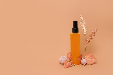 Essential oil for body or hair with autumn composition on orange bakground, cosmetic photography