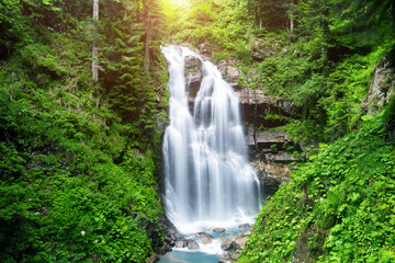 A mountain waterfall flows over the rocks. Deep rainforest waterfall view.