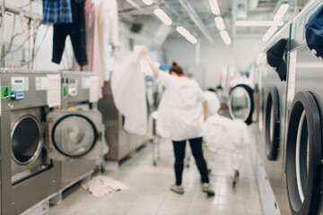 Dry cleaning worker loading clothes. Clean cloth chemical process. Laundry industrial dry-cleaning.