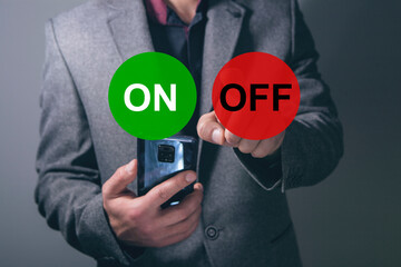 Buttons ON and OFF on a background of green and red. A man presses the screen while holding a phone...