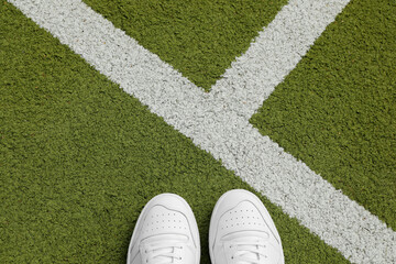 White sneakers on the green grass with white lines, no people