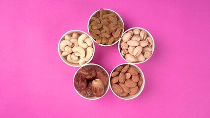 A variety mix of dried fruits and nuts on a pink background. Selective focus.Concept of Healthy...