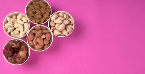 A variety mix of dried fruits and nuts on a pink background. Selective focus.Concept of Healthy fitness super food.