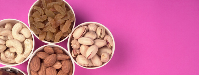 A variety mix of dried fruits and nuts on a pink background. Selective focus.Concept of Healthy fitness super food.