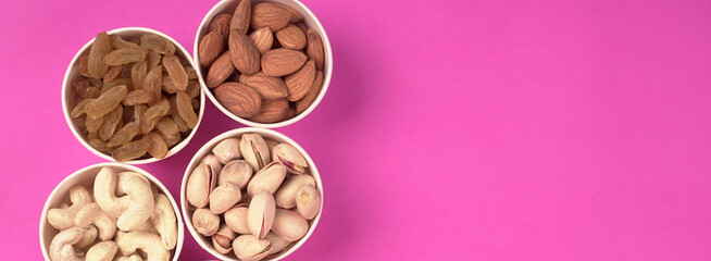 A variety mix of dried fruits and nuts on a pink background. Selective focus.Concept of Healthy fitness super food.