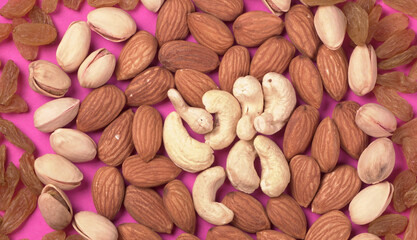 A variety mix of dried fruits and nuts on a pink background. Selective focus.Concept of Healthy fitness super food.