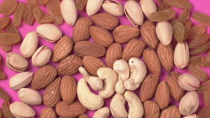 A variety mix of dried fruits and nuts on a pink background. Selective focus.Concept of Healthy fitness super food.