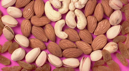A variety mix of dried fruits and nuts on a pink background. Selective focus.Concept of Healthy...