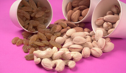 A variety mix of dried fruits and nuts on a pink background. Selective focus.Concept of Healthy...