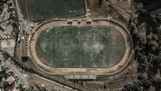 Old abandoned football stadium. Remains of a green lawn. Shabby abandoned stadium.