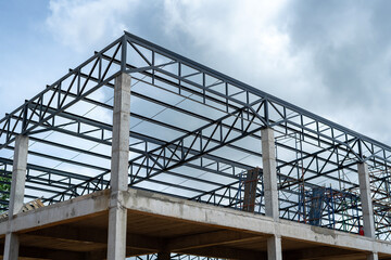 Factory building structure with cement base and steel frame for metal sheet roofing.