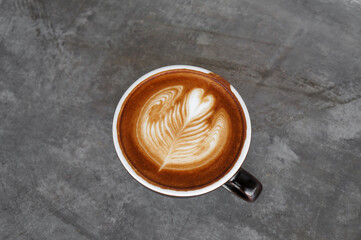 Top view of hot coffee in cup with heart shape latte art on dark brown old table at caff food and drink concept.
